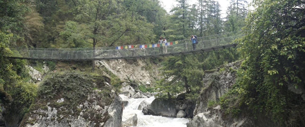 Trekkers crossing a suspension bridge on the Manaslu Circuit Trek in Nepal, with scenic Himalayan landscapes โ Manaslu Circuit Trek permit guide.