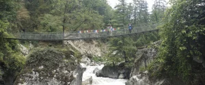 Trekkers crossing a suspension bridge on the Manaslu Circuit Trek in Nepal, with scenic Himalayan landscapes โ Manaslu Circuit Trek permit guide.