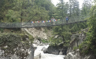Trekkers crossing a suspension bridge on the Manaslu Circuit Trek in Nepal, with scenic Himalayan landscapes — Manaslu Circuit Trek permit guide.